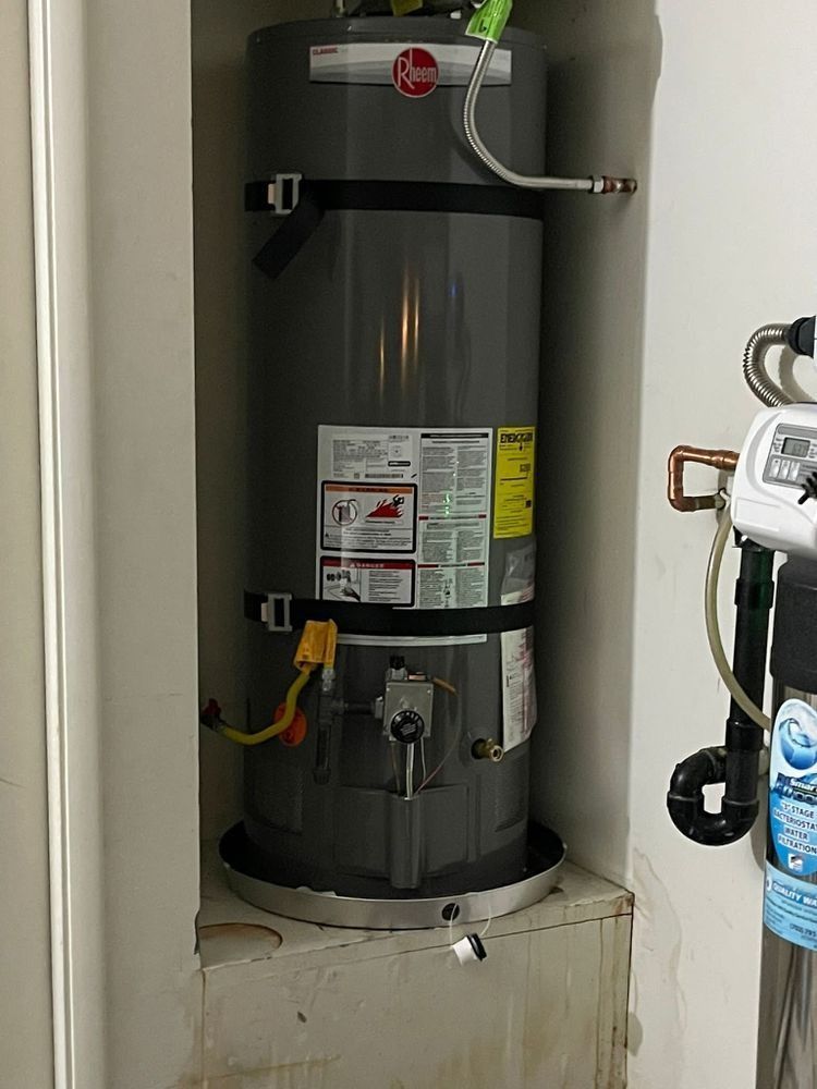 A gray water heater is sitting in a corner of a room.