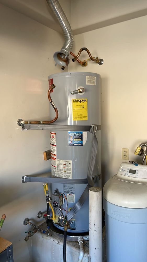 A water heater is sitting next to a washing machine in a laundry room.