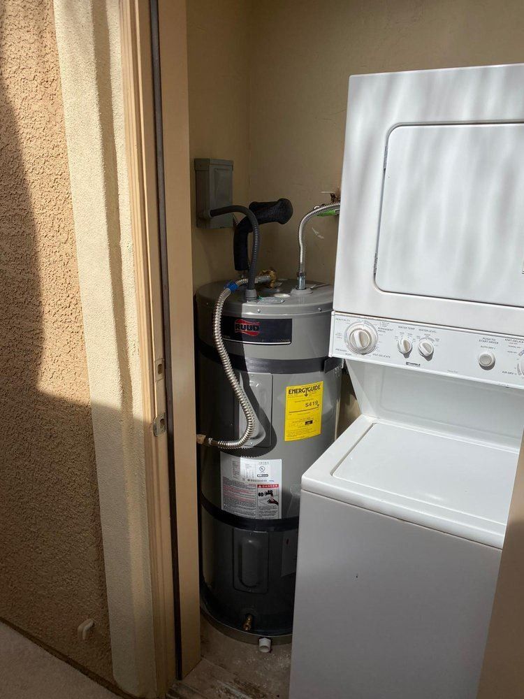A water heater is sitting next to a washer and dryer in a laundry room.