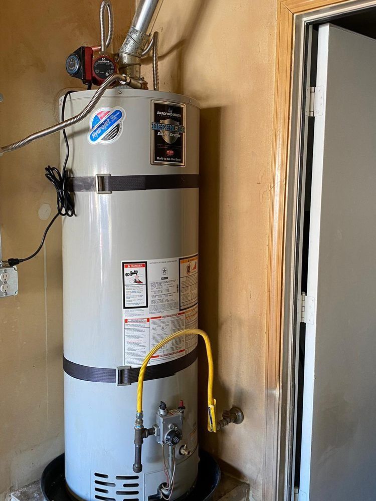 A water heater is sitting in a room next to a door.