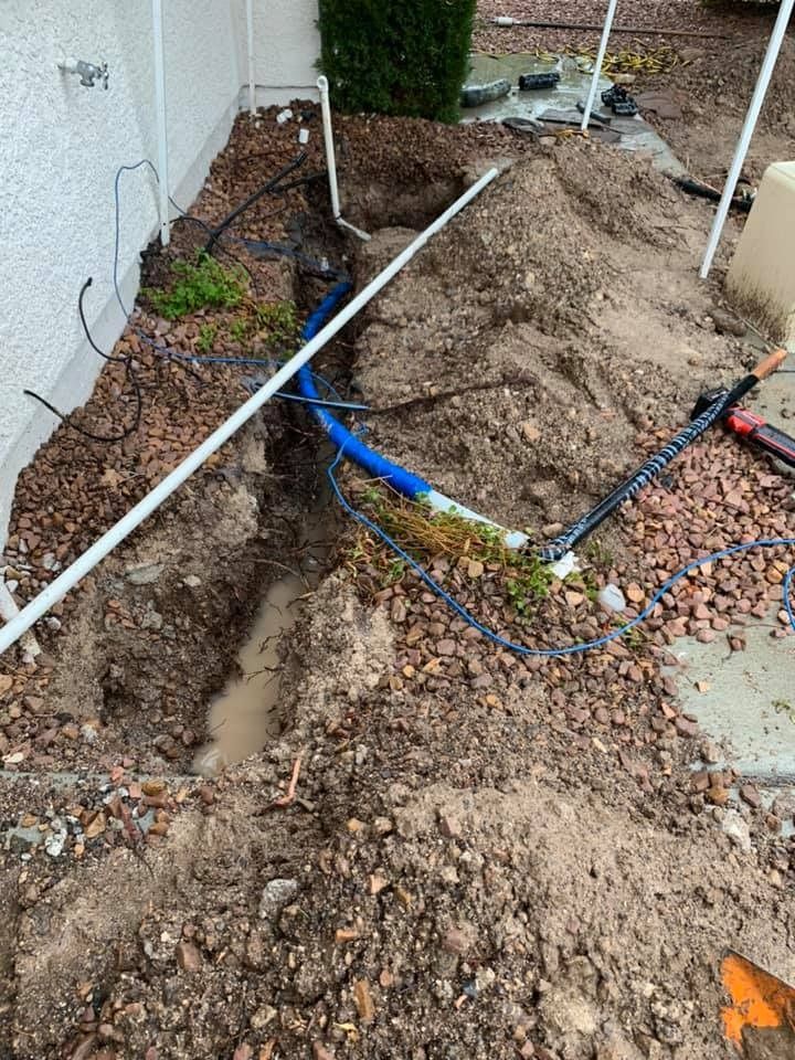 A pipe is being installed in the dirt next to a house.
