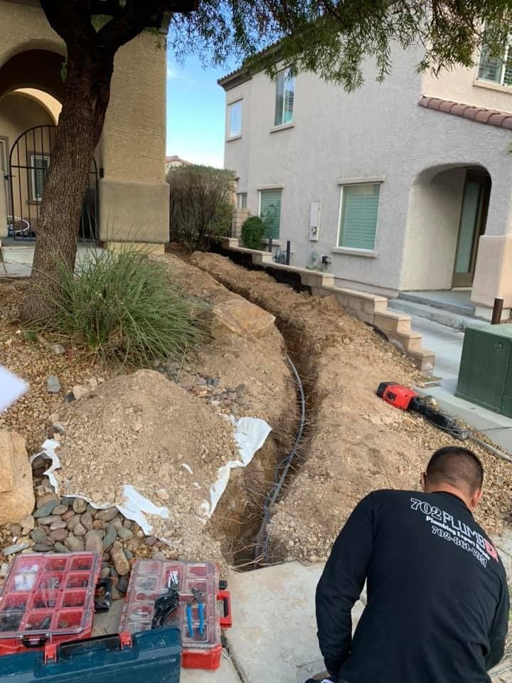 A man is kneeling down in the dirt in front of a house.