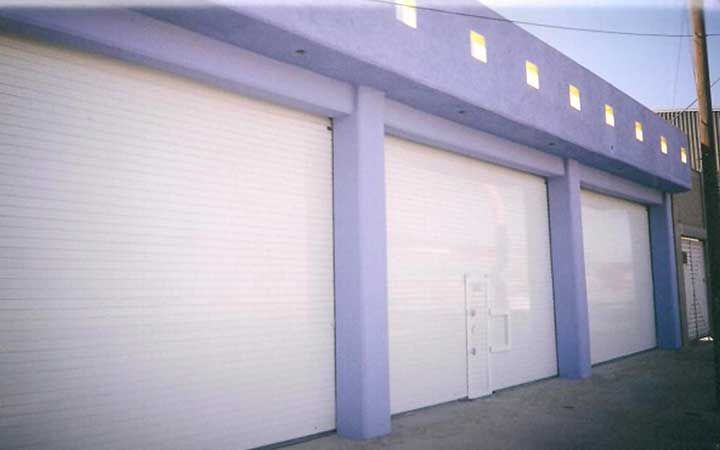 Una hilera de puertas de garaje blancas en un edificio morado