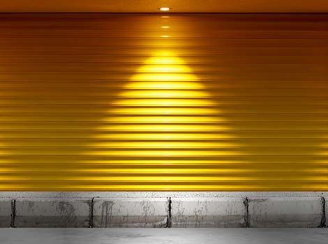 Un primer plano de una puerta de garaje amarilla con una luz brillando a través de ella.