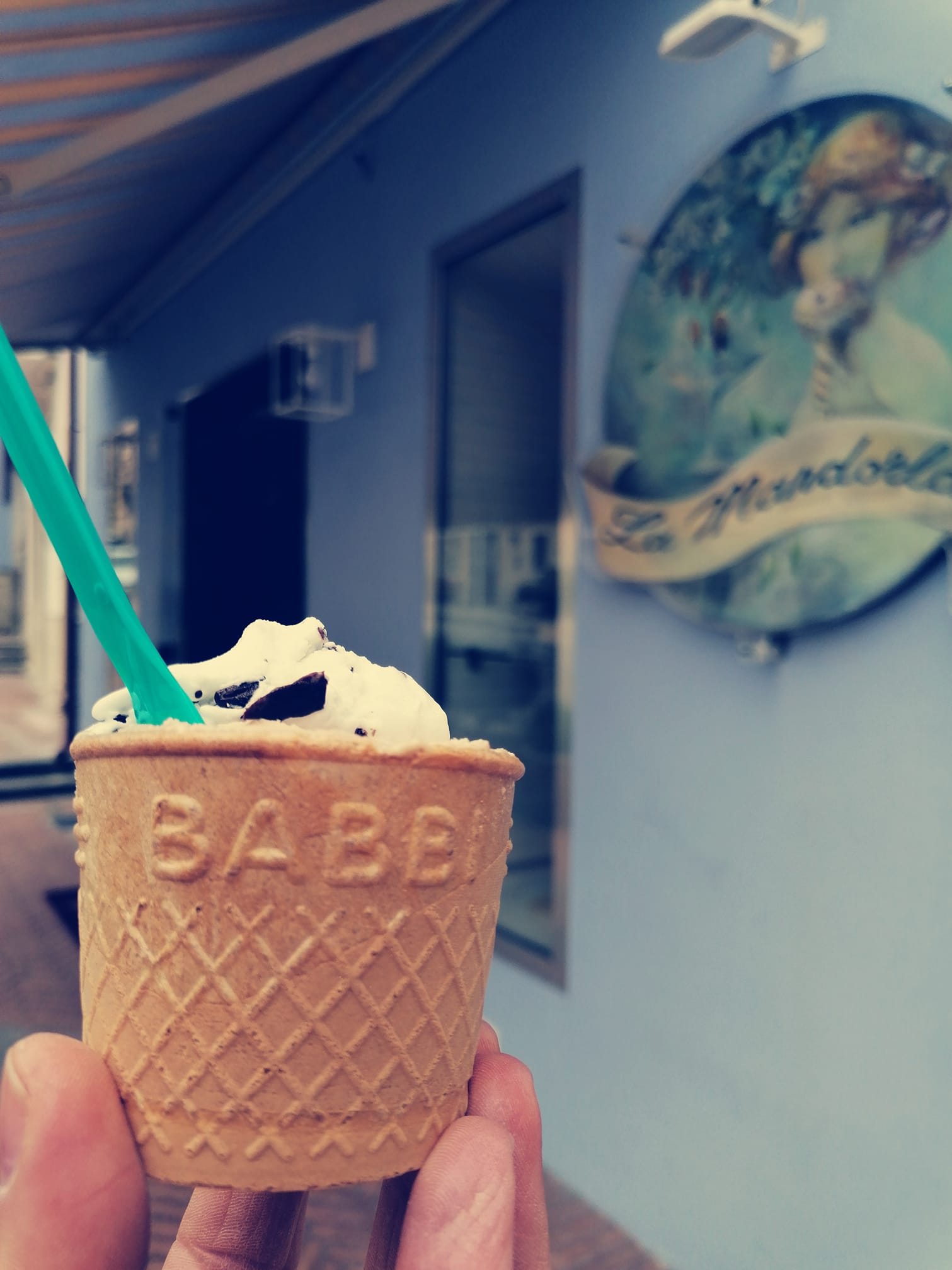 Una persona tiene in mano un cono gelato con la scritta