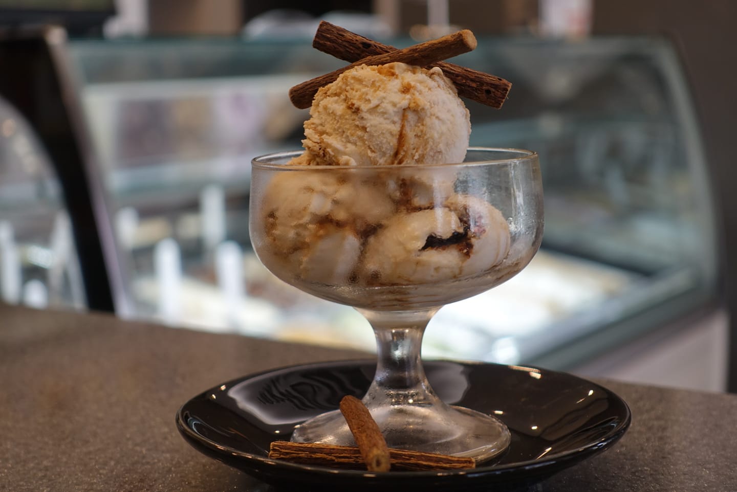 Un bicchiere di gelato con bastoncini di cannella sopra.