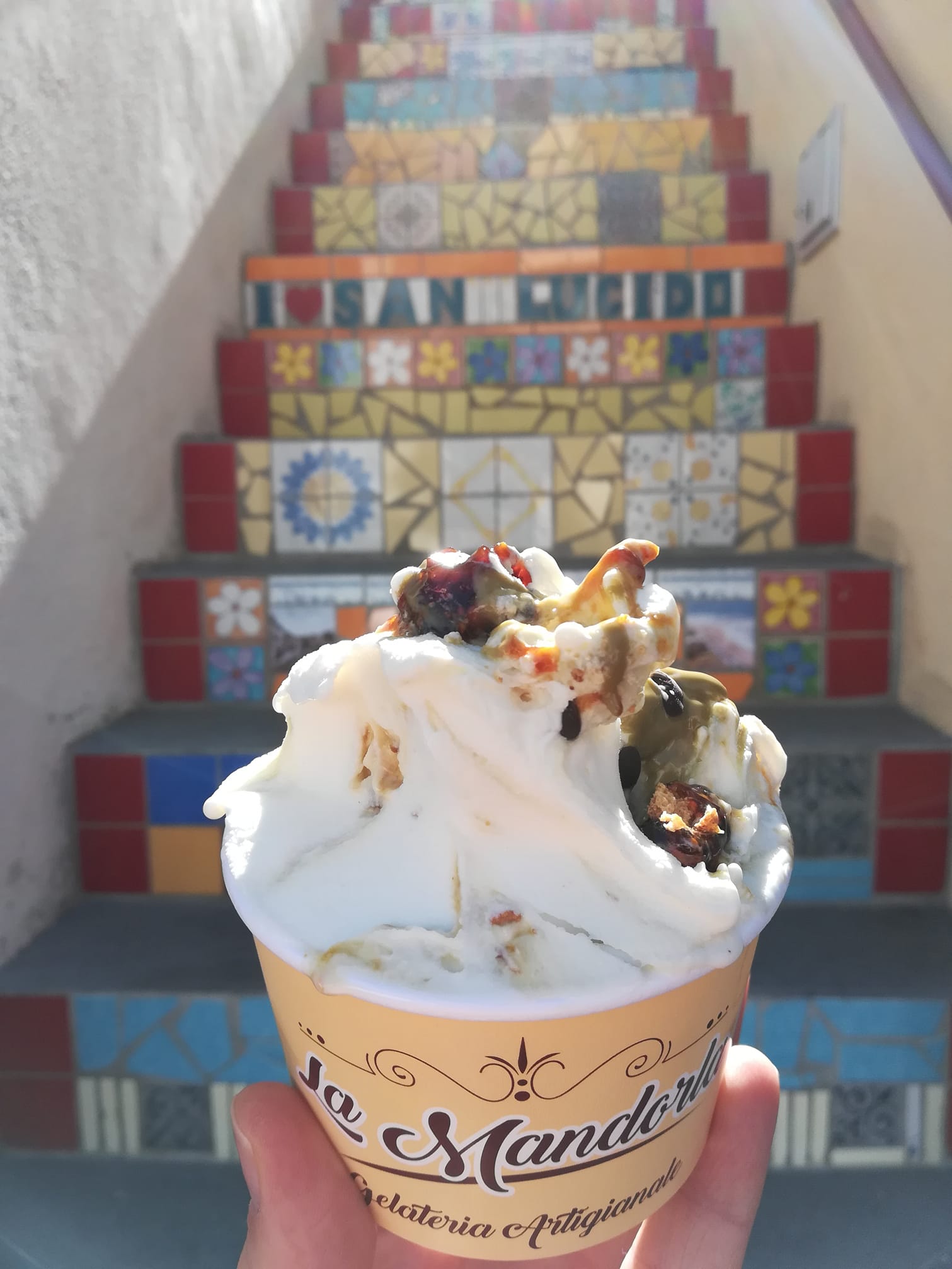 Una persona tiene in mano una coppa di gelato davanti alle scale