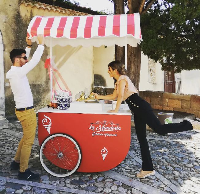 Un uomo e una donna in piedi davanti a un carretto dei gelati