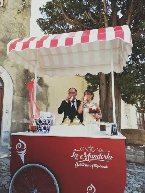 Una coppia di sposi che beve da un carretto dei gelati con la scritta la mandorla