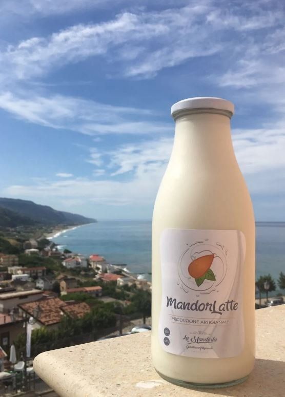 Una bottiglia di latte alle mandorle è appoggiata su un balcone con vista sull'oceano