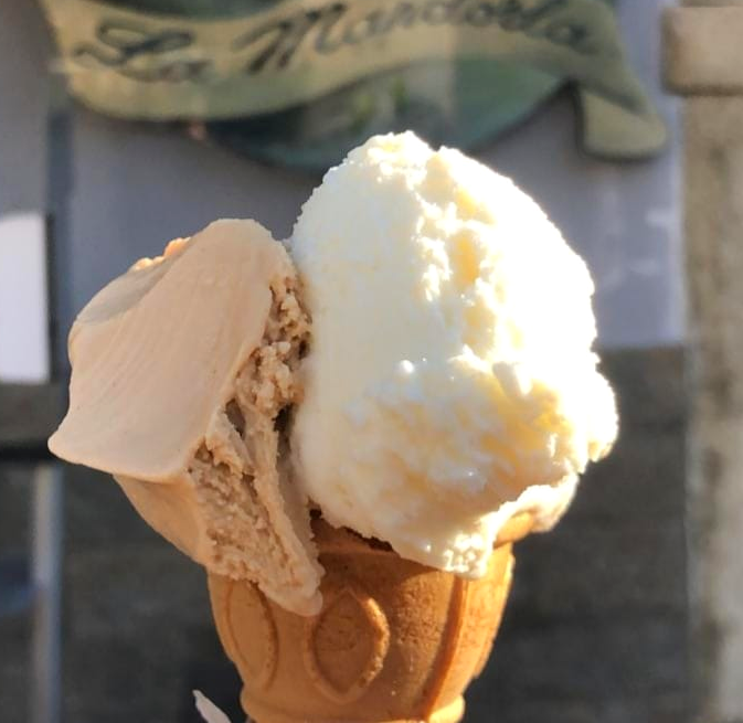 Un primo piano di un cono gelato davanti a un cartello che dice la mandola