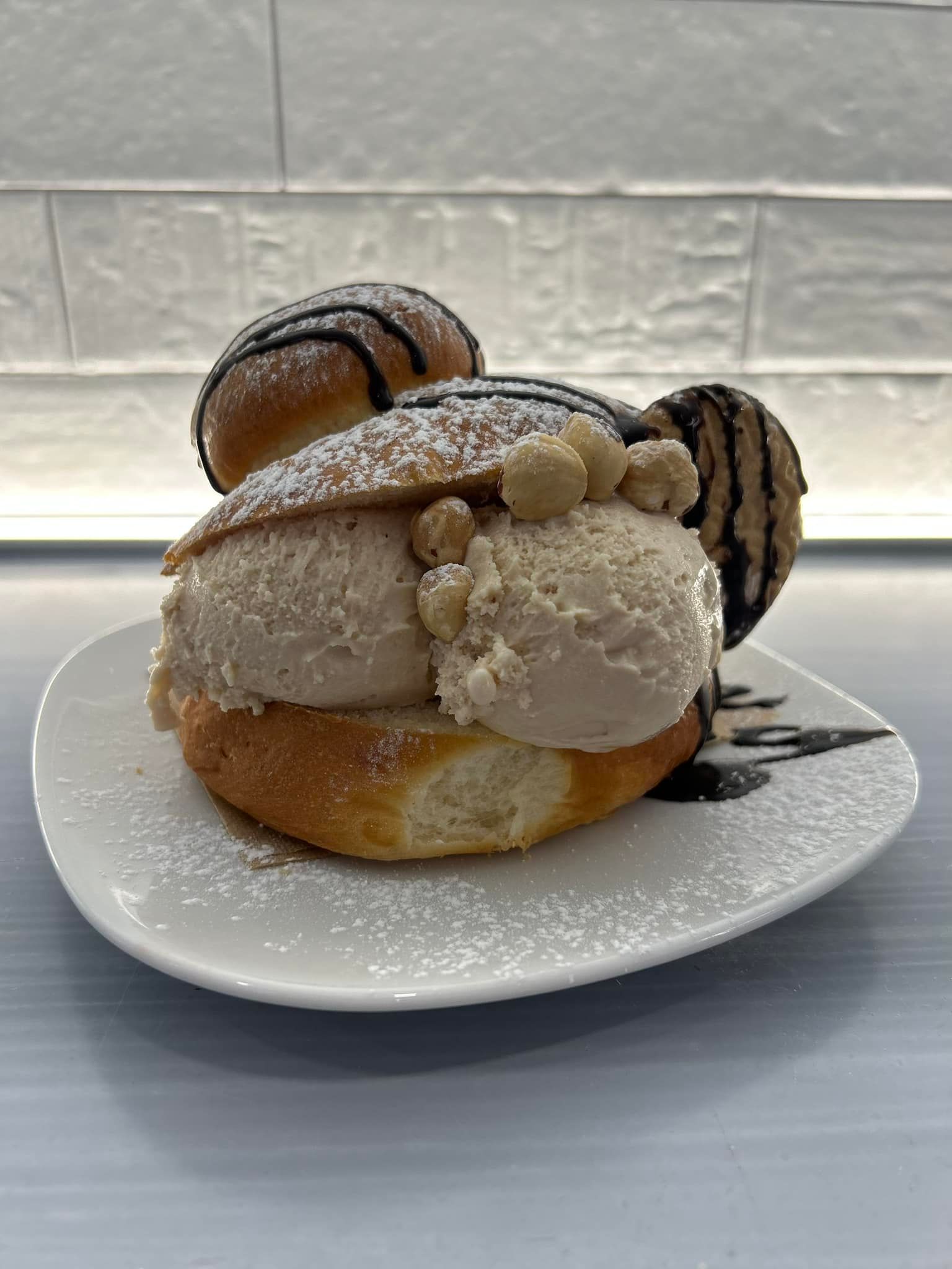 Un panino con gelato e noci su un piatto bianco.
