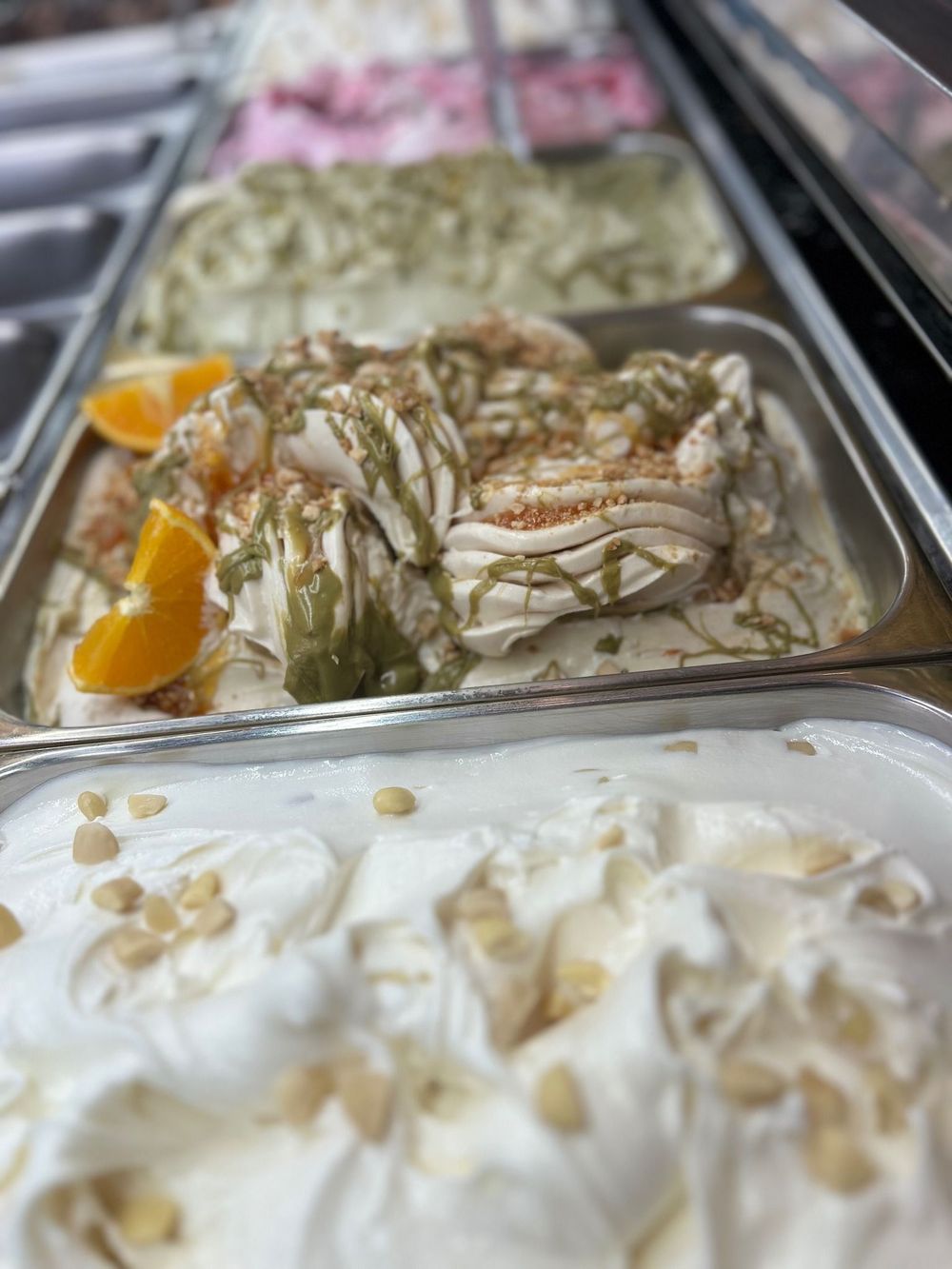 Primo piano di una vaschetta di gelato con noci sopra.