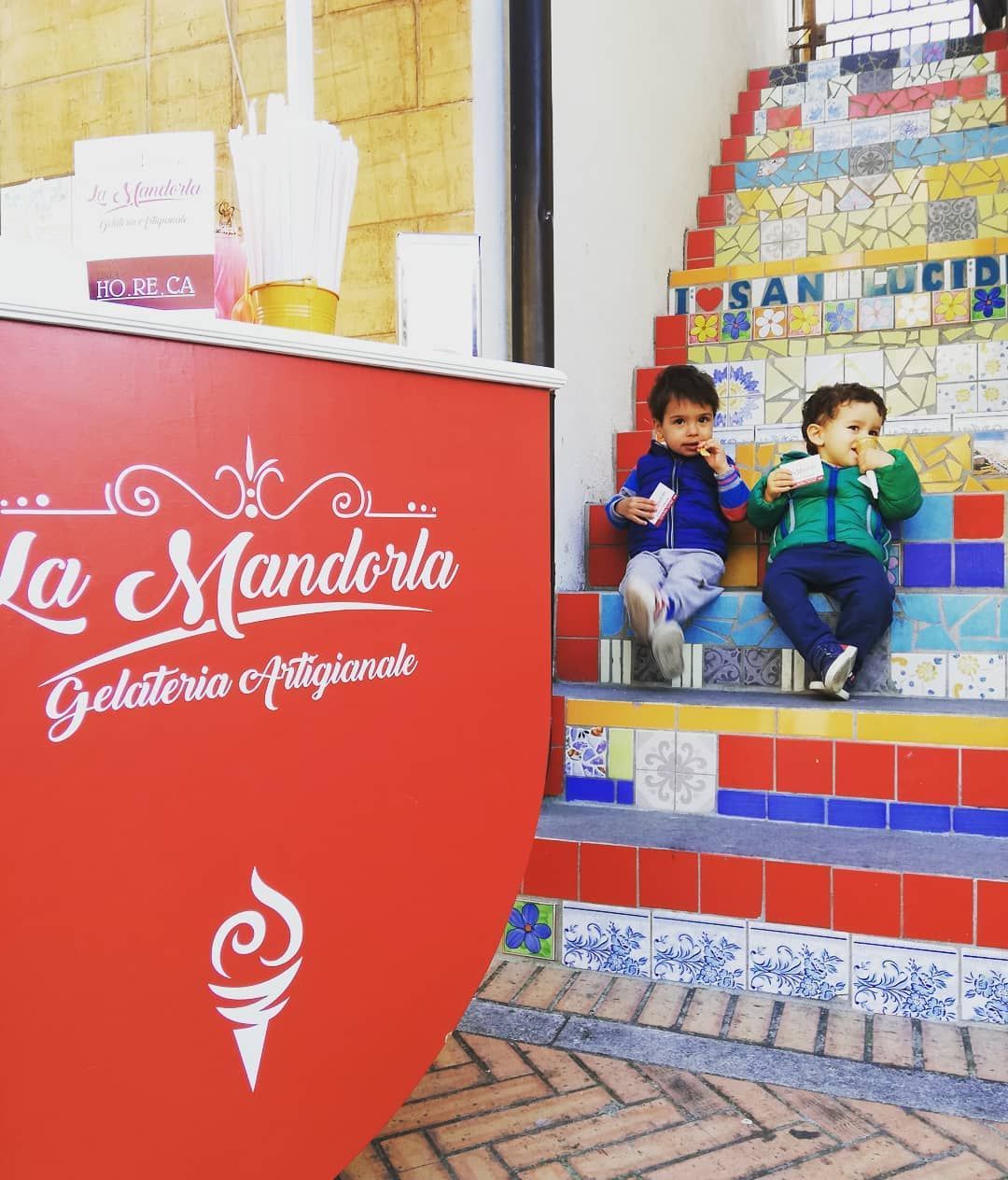 Due bambini sono seduti su una rampa di scale e mangiano un gelato