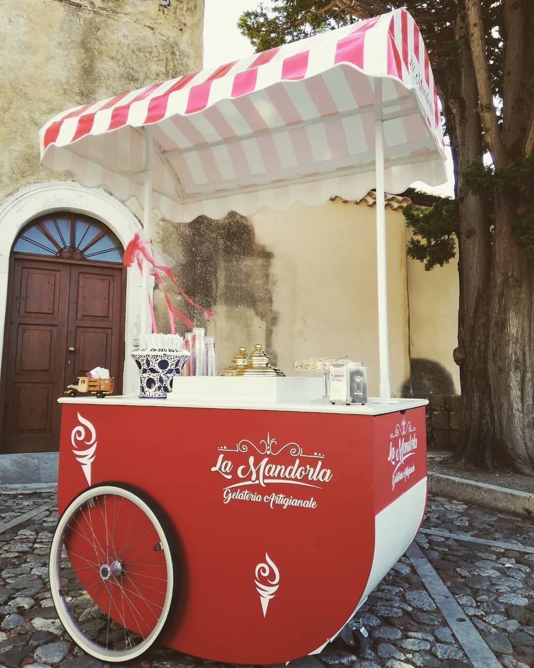 Un carretto dei gelati rosso e bianco con una tenda a strisce rosa e bianche