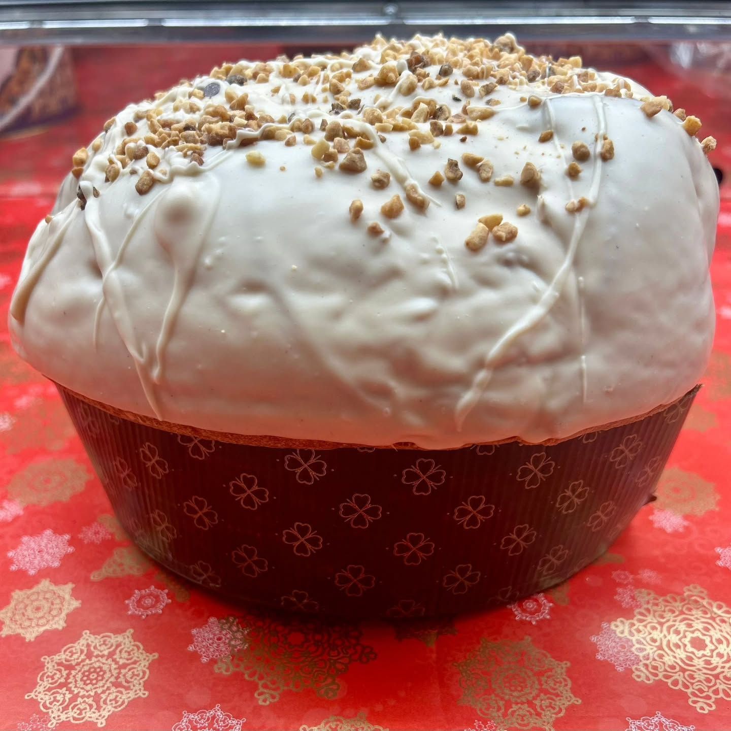 Su un tavolo c'è un panettone con glassa bianca e noci sopra.