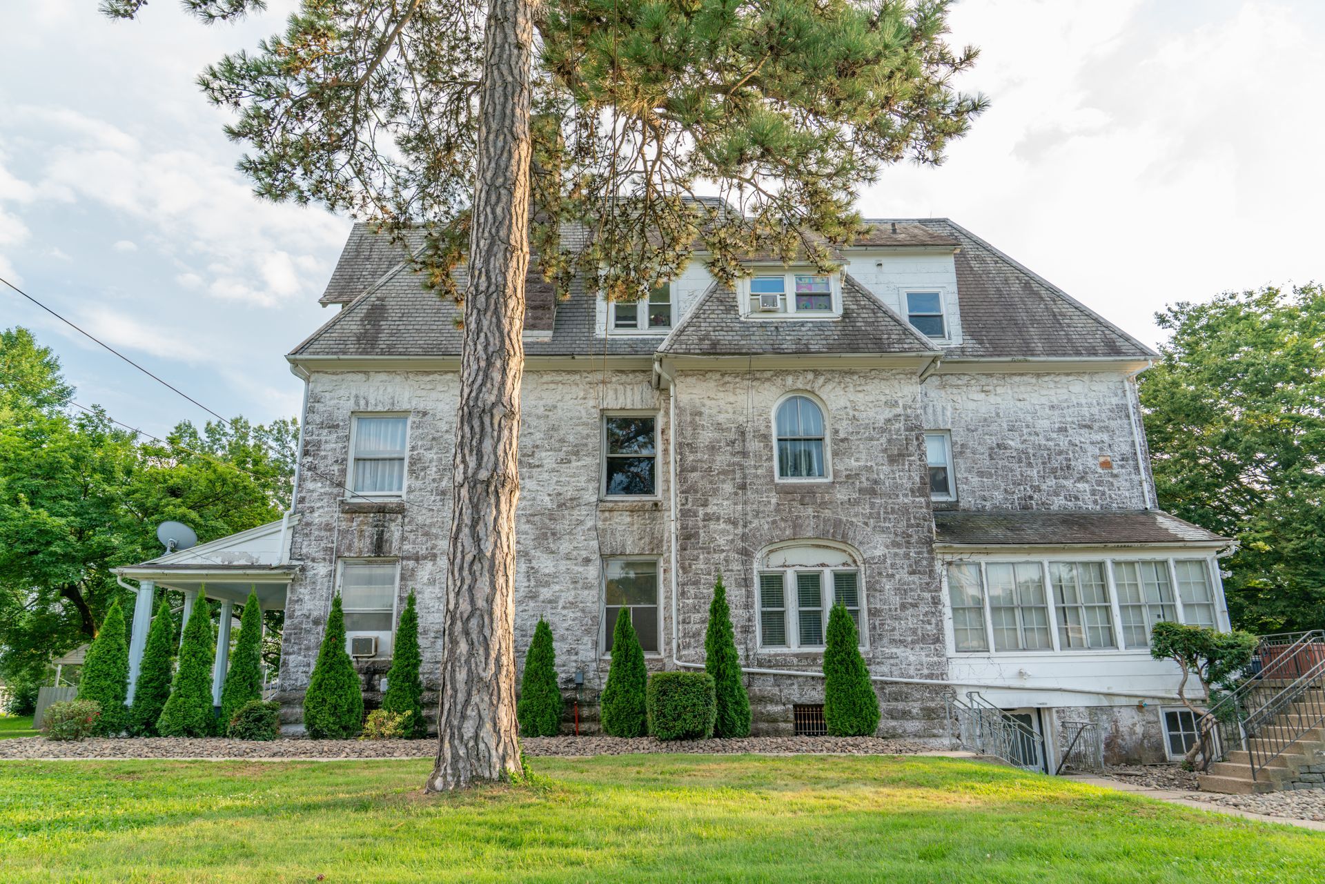 Photo of a large 3 story brick or stone building with a large lawn surrounding it