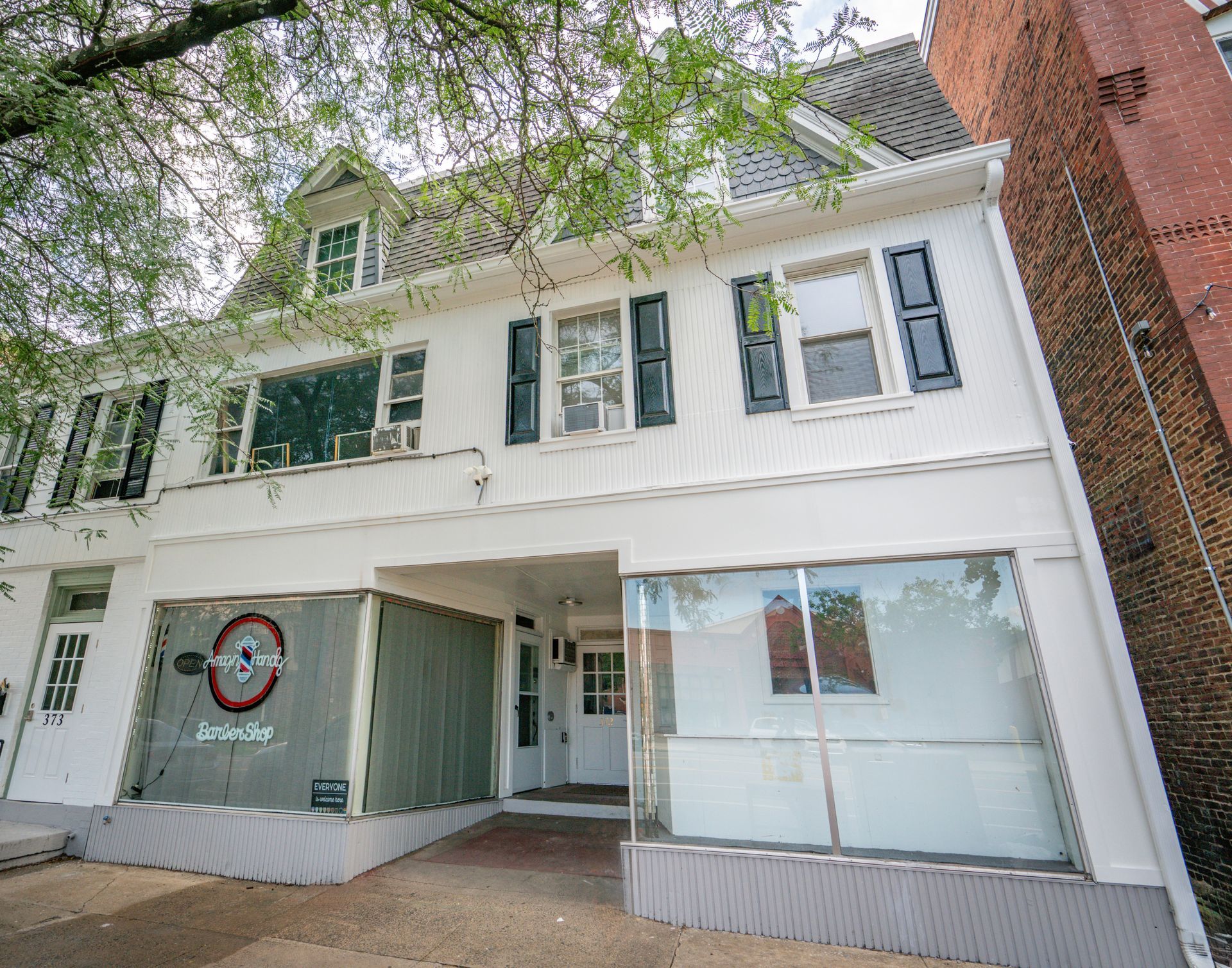Photo of a building exterior showing a commercial space on the first floor and apartments on the second and third floors, seen looking up from the sidewalk