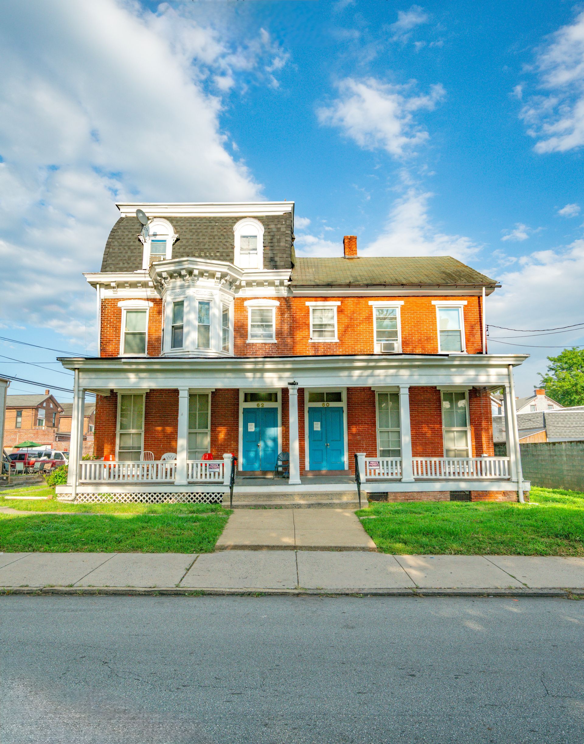 Front-facing photo of an old home, 3 stories with red brick and black and white features