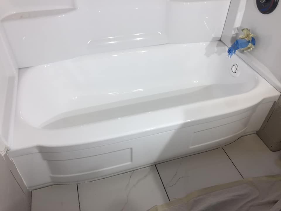 A white, modern bathtub installed in a bathroom with white tiled flooring.