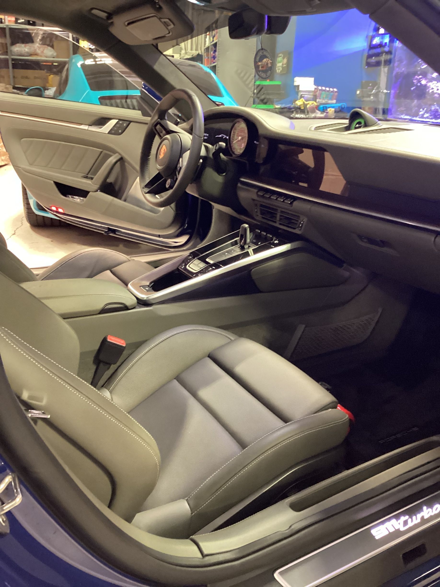 Interior of a blue Porsche 911 Turbo with grey seats, steering wheel, and dashboard.