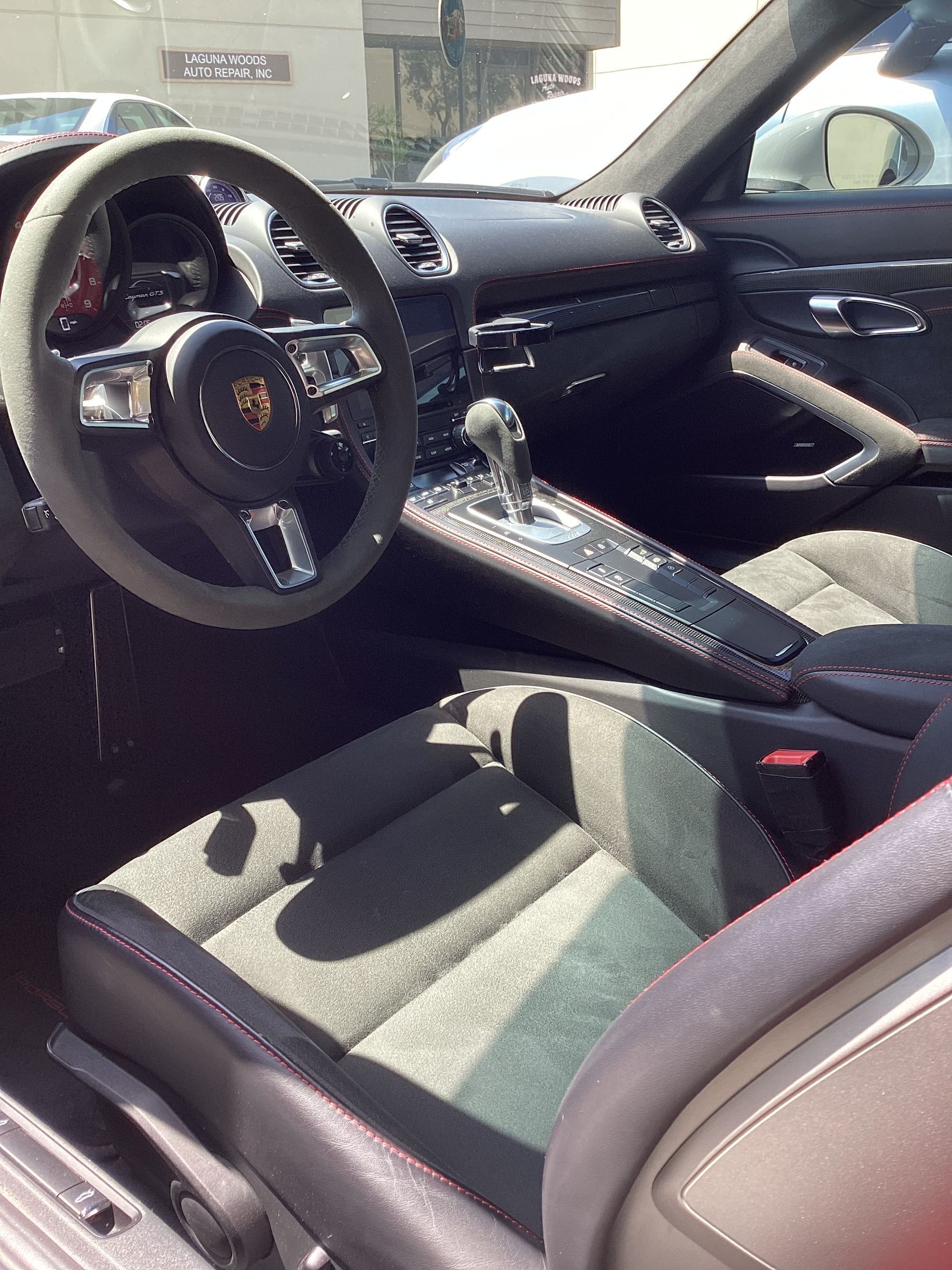 Interior of a Porsche sports car with gray and black accents; steering wheel, seats, and console visible.
