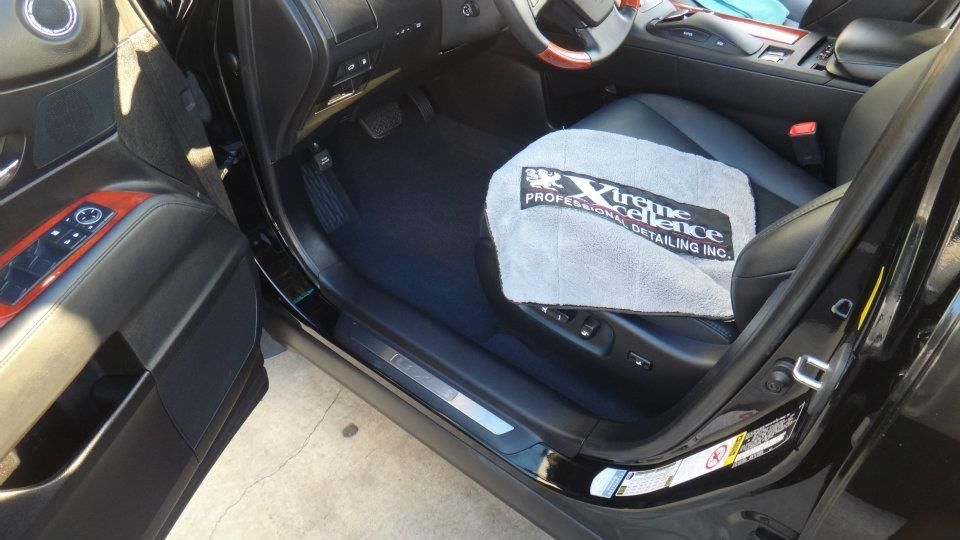 Interior shot of a black vehicle with the driver-side door open, showing a clean cabin and a branded 