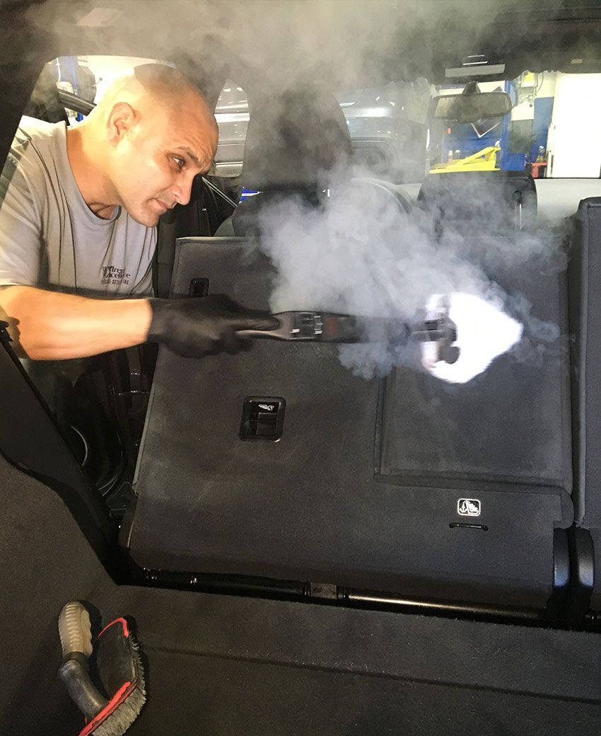 Interior shot of a black vehicle with the driver-side door open, showing a clean cabin and a branded 