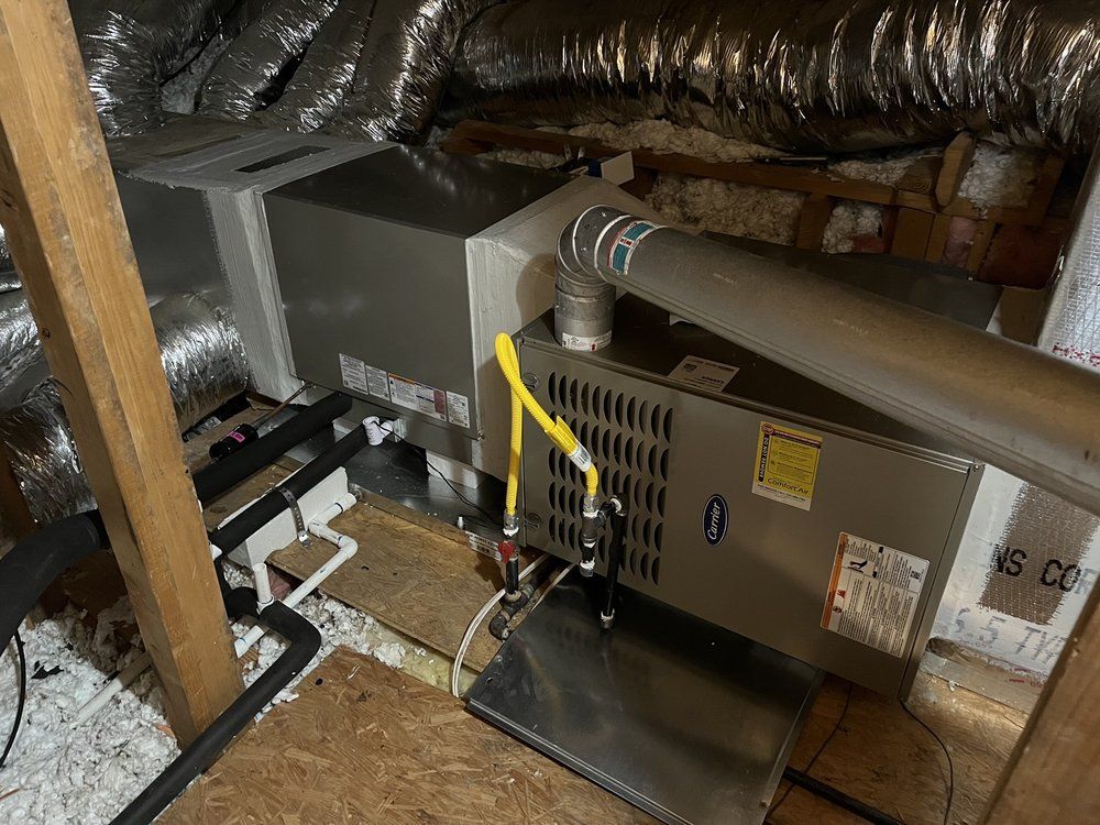 HVAC unit in an attic setting, with metal components, ductwork, and insulation visible. Electrical wiring
