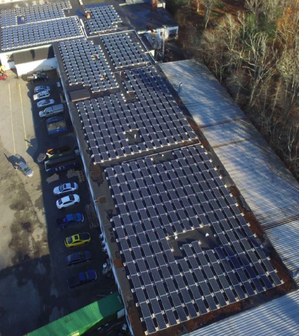 An aerial view of a car dealership with solar panels on the roof.