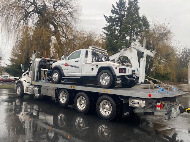A white truck is sitting on top of a flatbed tow truck.