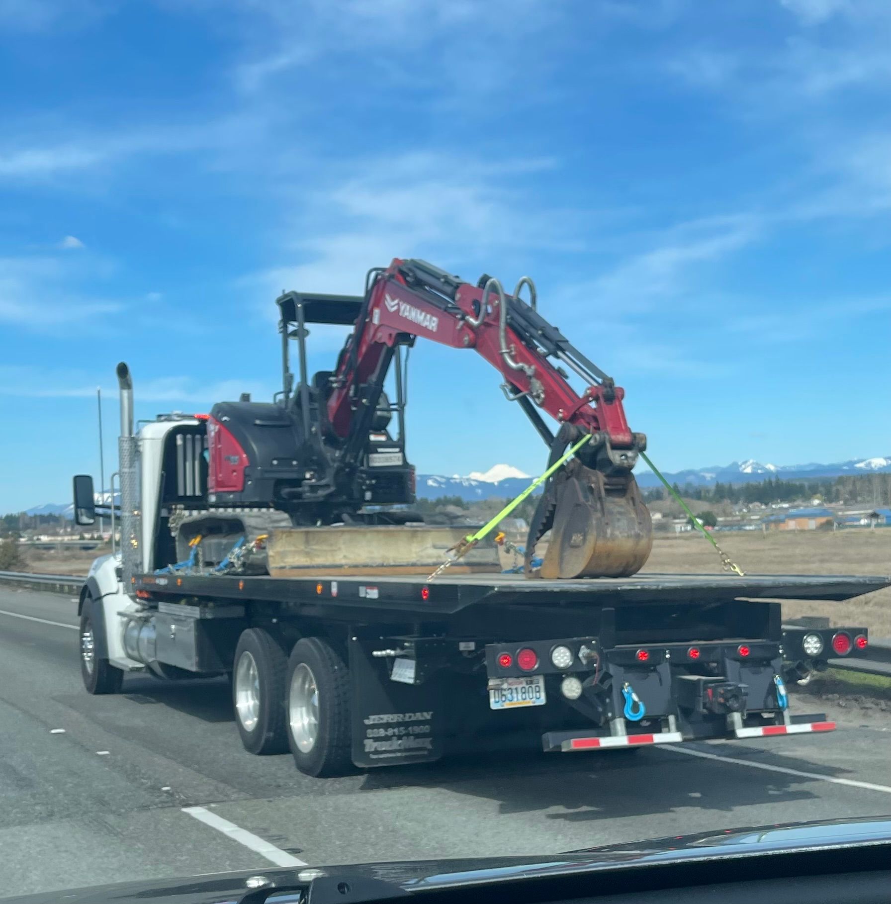 A tow truck with an excavator on the back of it