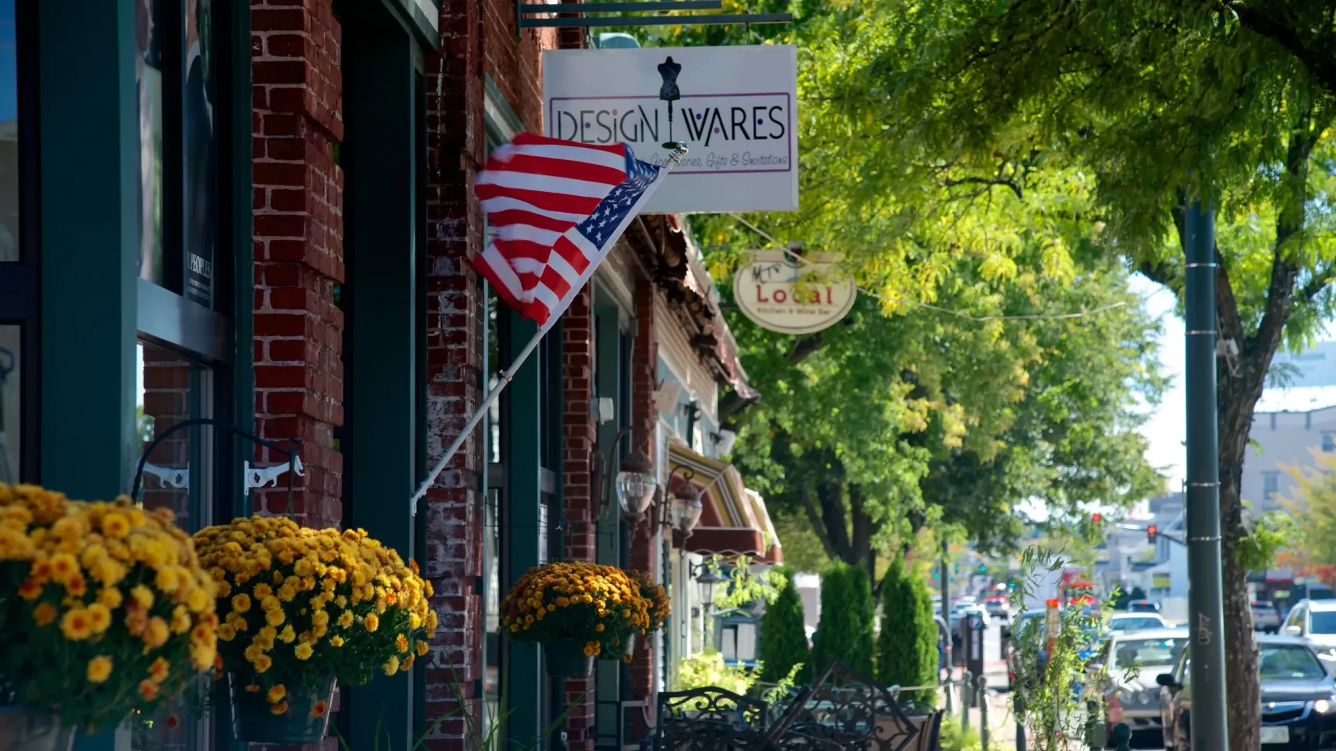A flag is hanging from the side of a building on a city street.