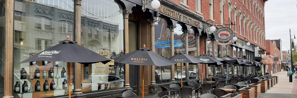A restaurant with tables and umbrellas outside of it.