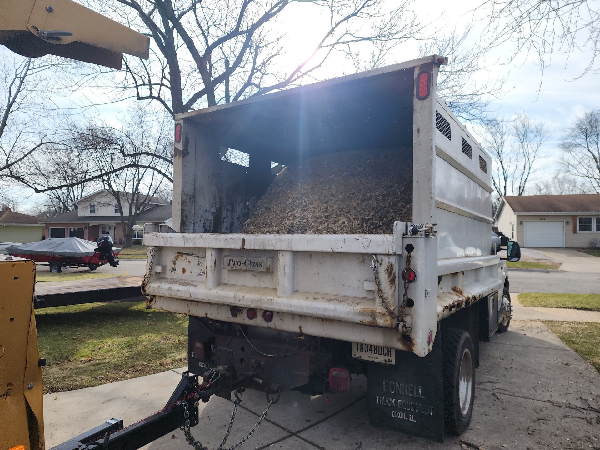 A dump truck is parked in a driveway with the back door open.