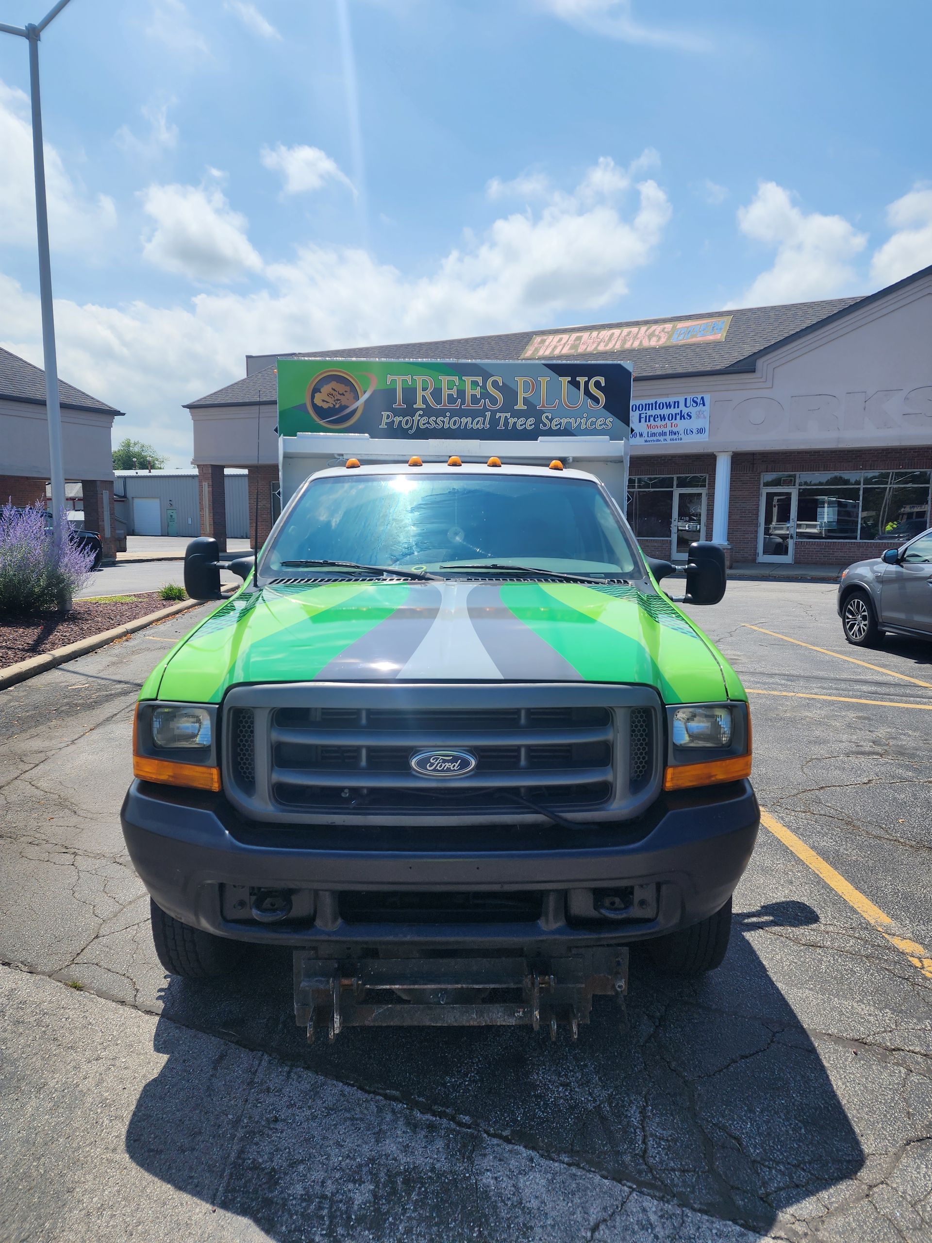 A green truck is parked in a parking lot in front of a building.