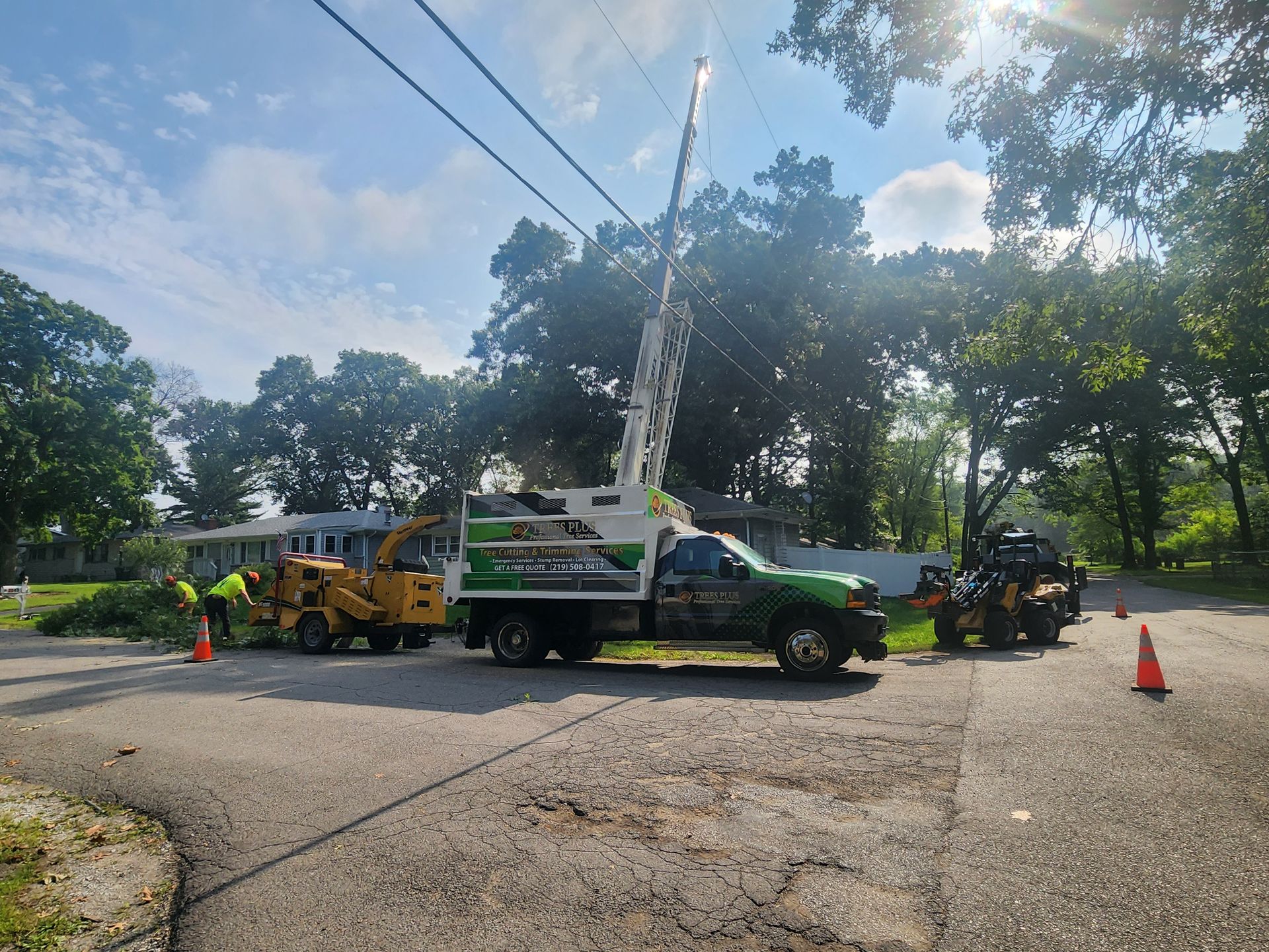 A Trees Plus truck is parked on the side of a Portage, Indiana road next to a tree chipper.