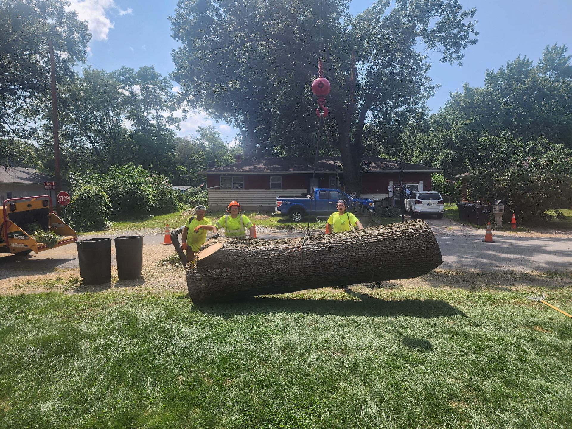 Two men are standing next to a large log in the grass.