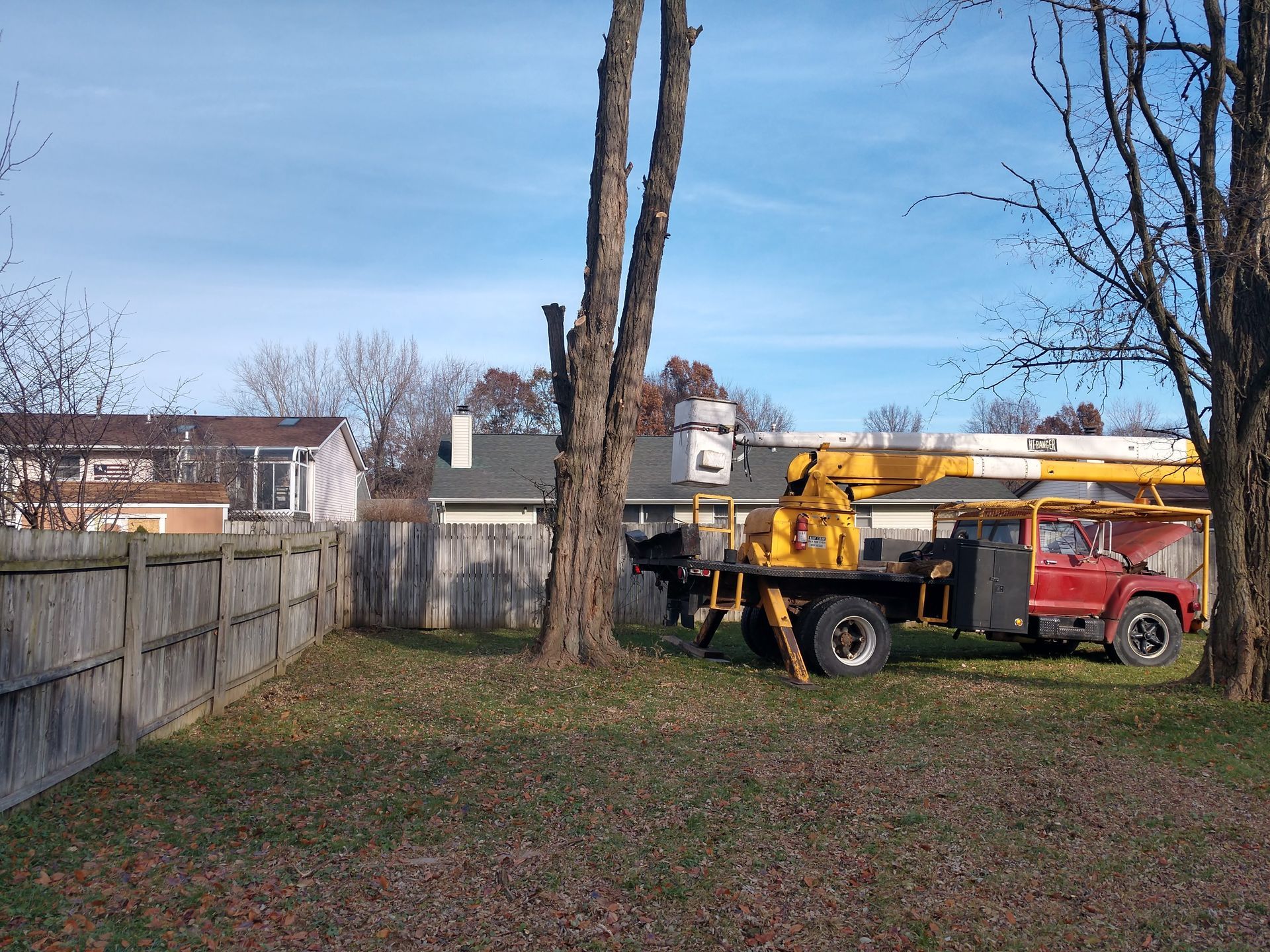 A red truck with a crane on the back is parked in a yard