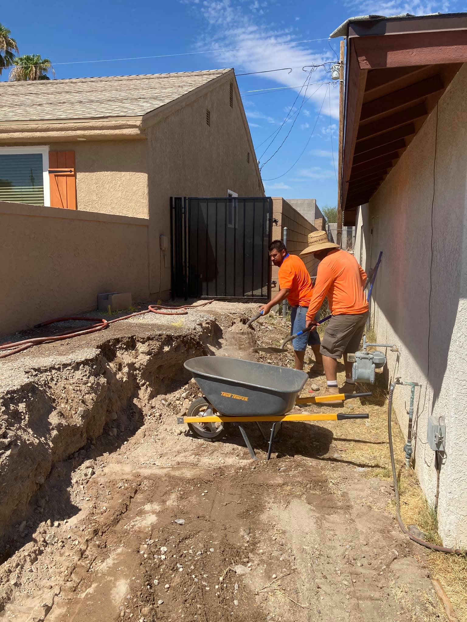 A group of construction workers are working on a sidewalk next to a house.