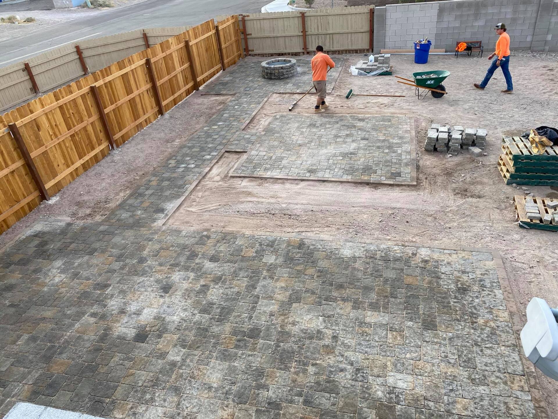 A group of people are working on a concrete floor in a backyard.