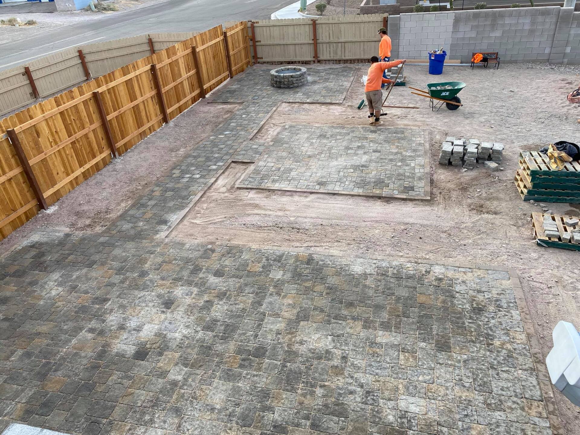 A group of people are working on a patio in a backyard.