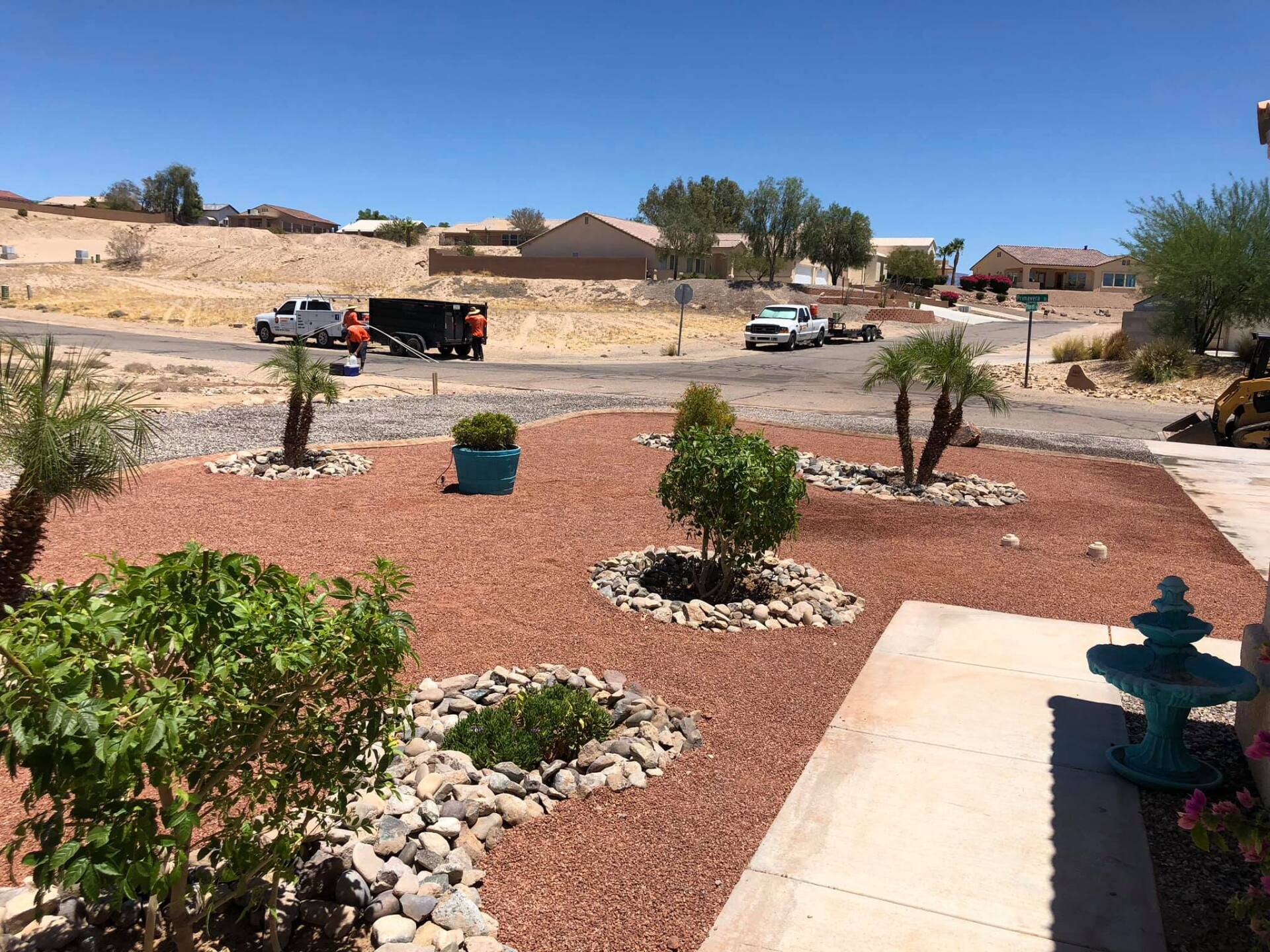 A garden with a fountain and a truck parked in the background.