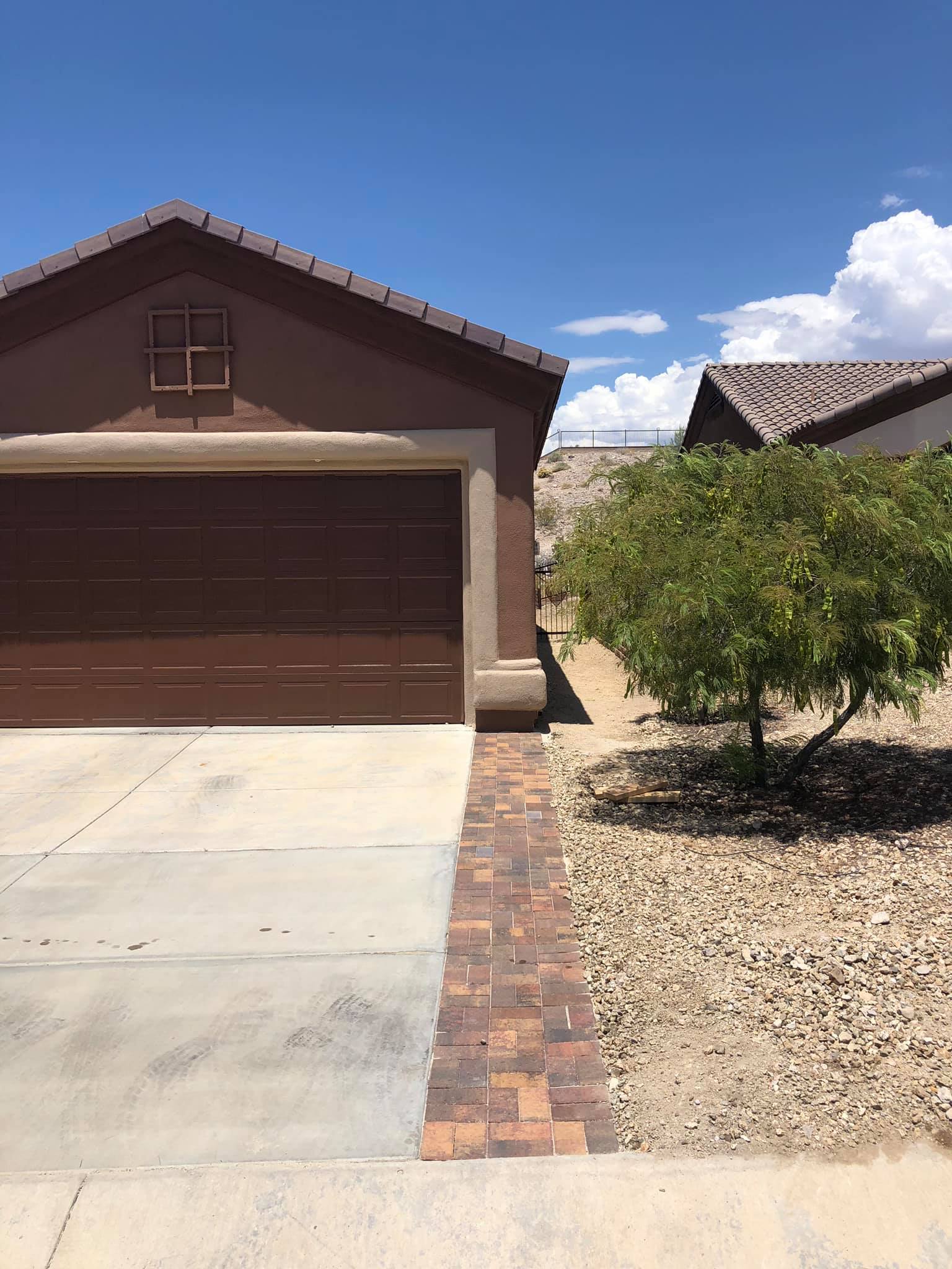 A house with a brown garage door and a brick walkway leading to it.