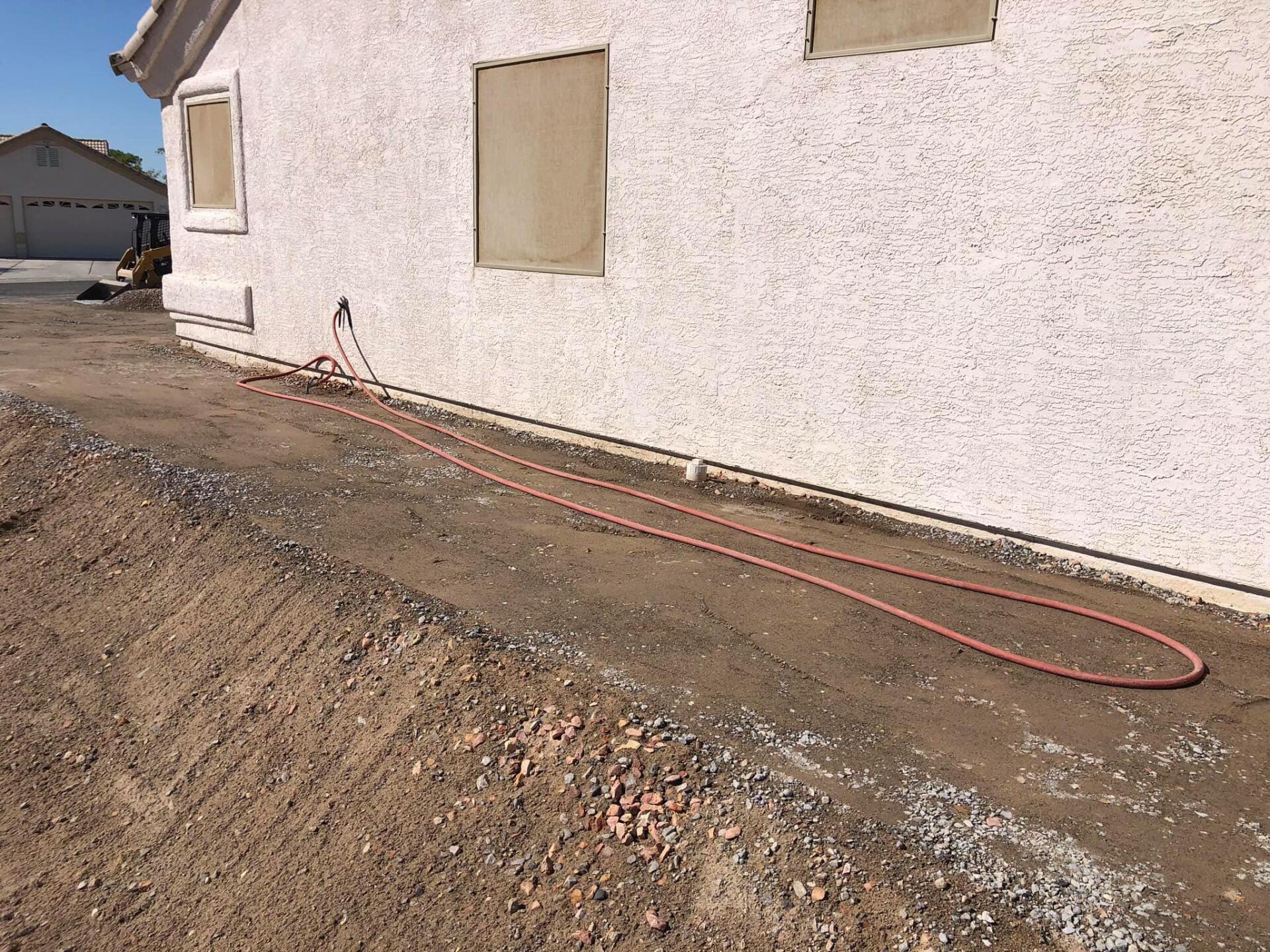 A hose is laying on the ground in front of a house.