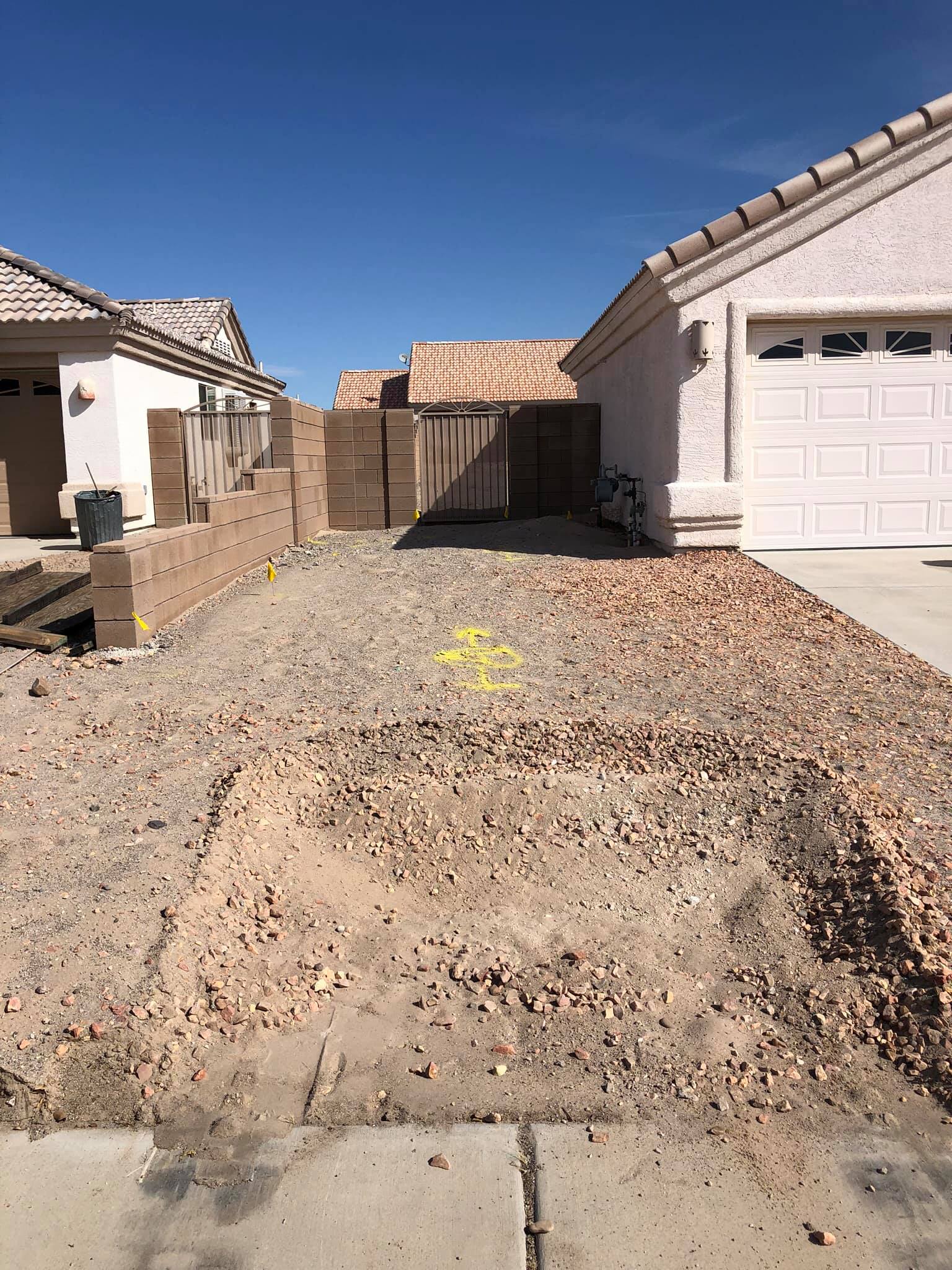 A dirt driveway leading to a house in a residential area.
