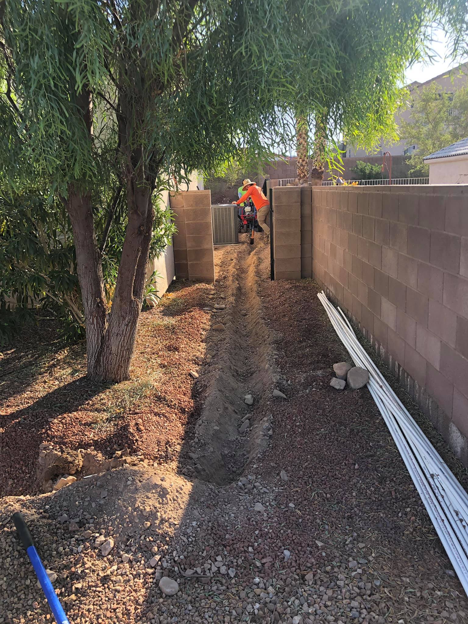 A man is standing next to a brick wall in a backyard.