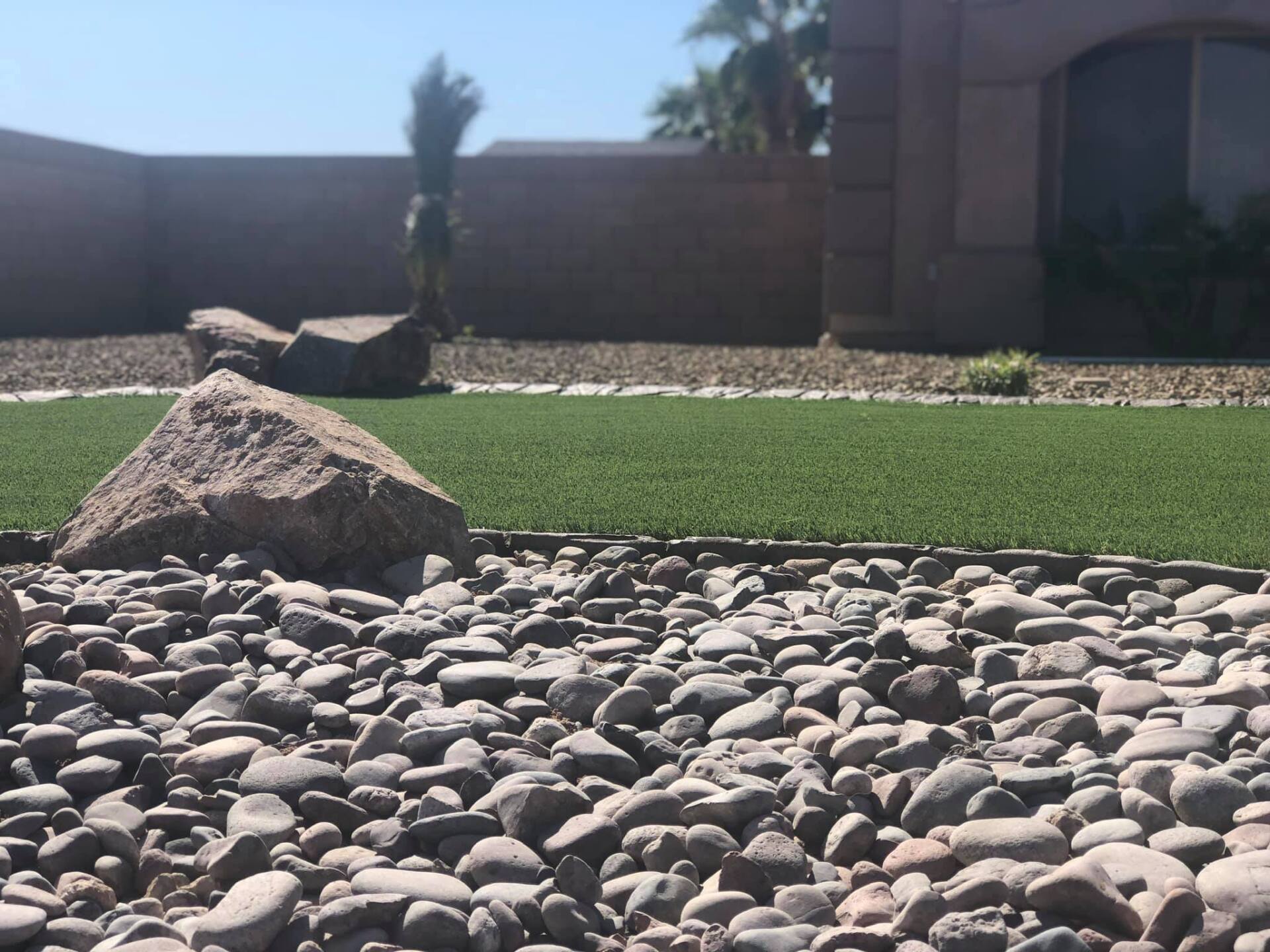 A lawn with rocks and grass in front of a house.