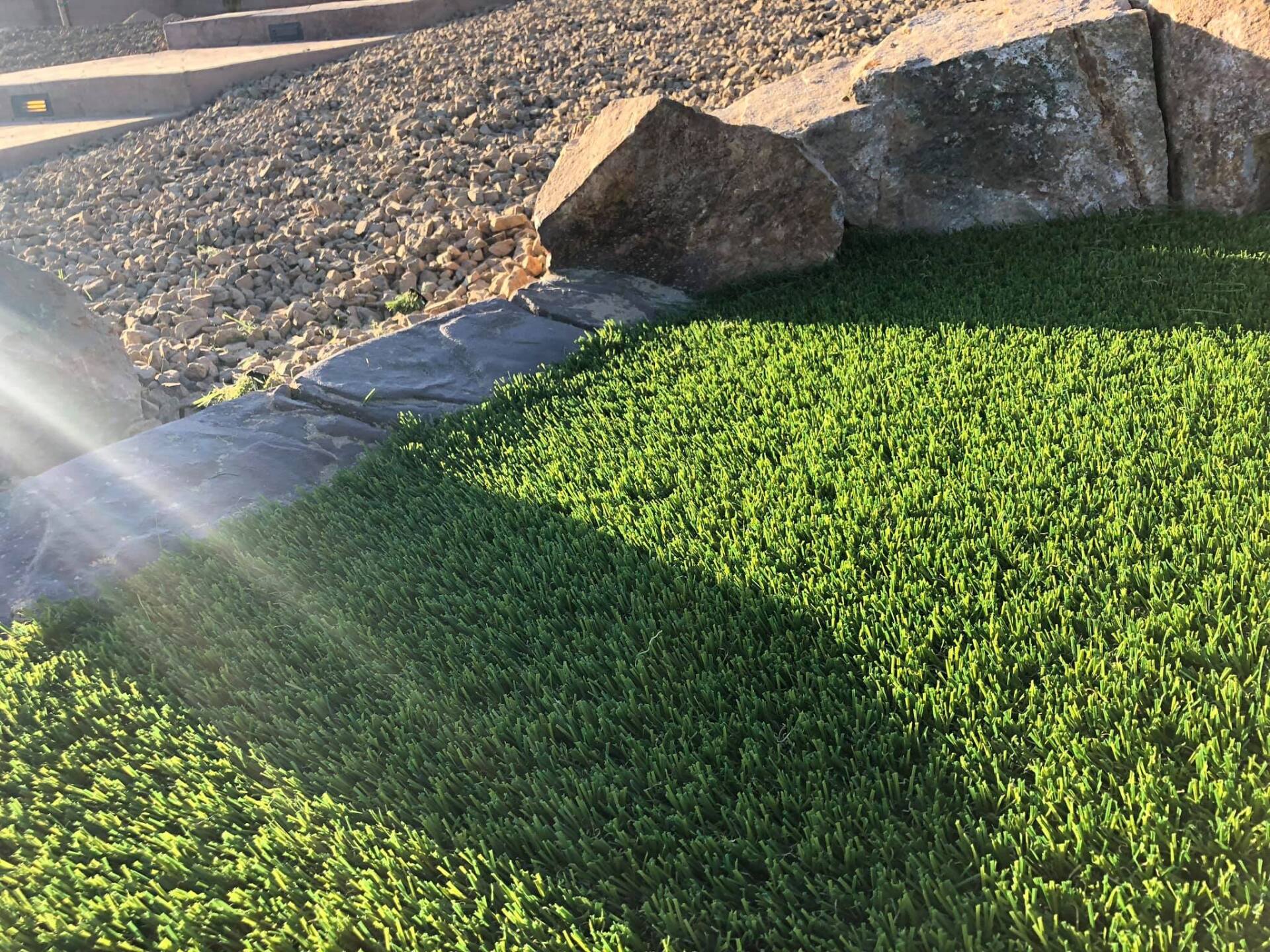 A close up of a lush green lawn with rocks in the background.