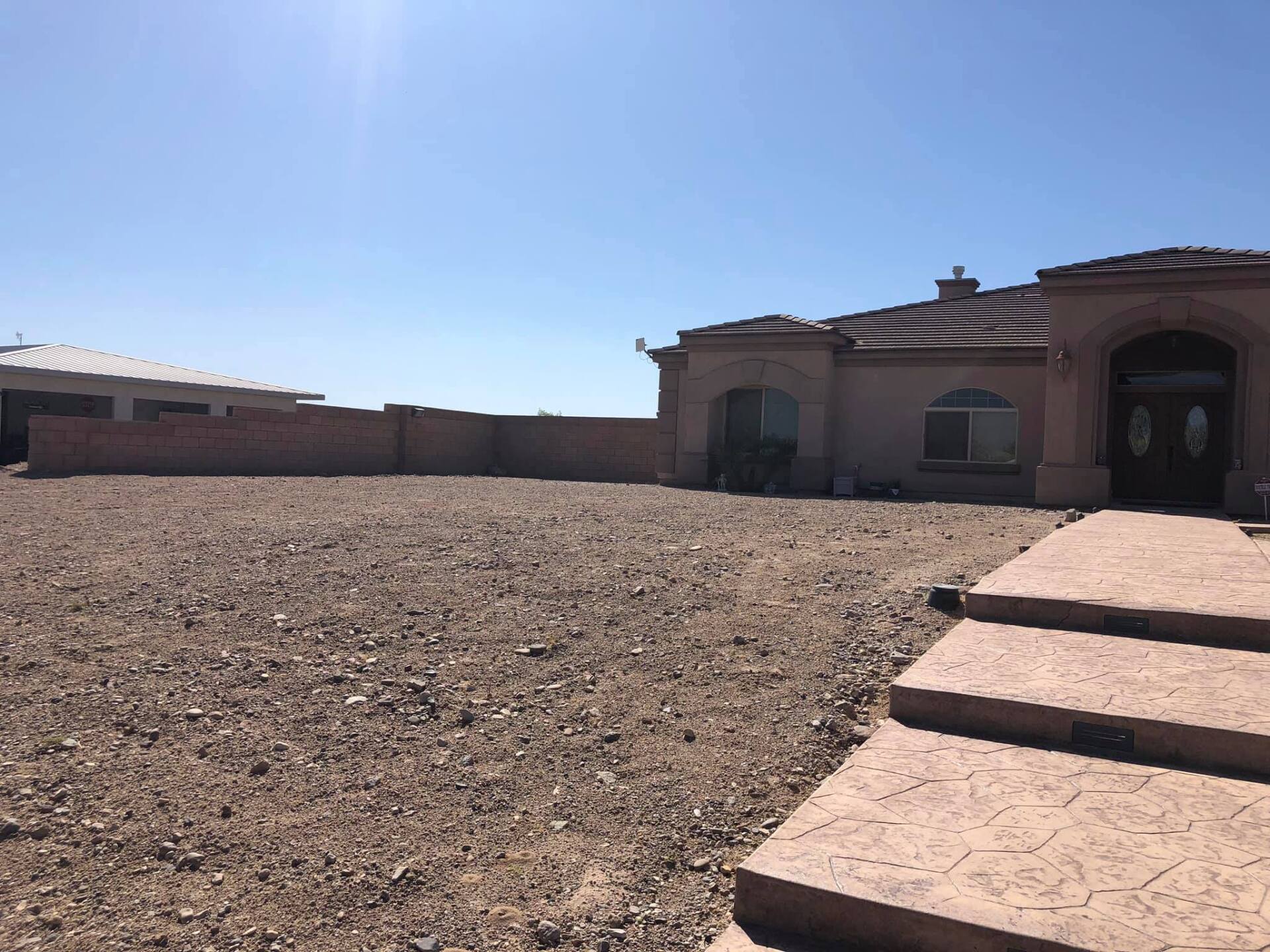 A large house is sitting in the middle of a dirt field.